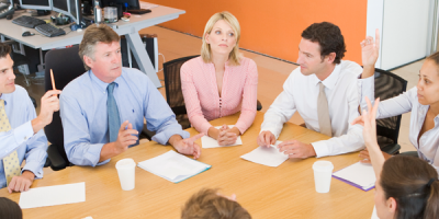 People in a conference, sitting around a table.