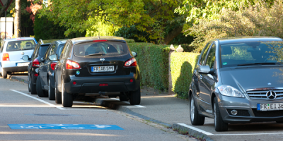 Cars parking on both sides of a suburban street.